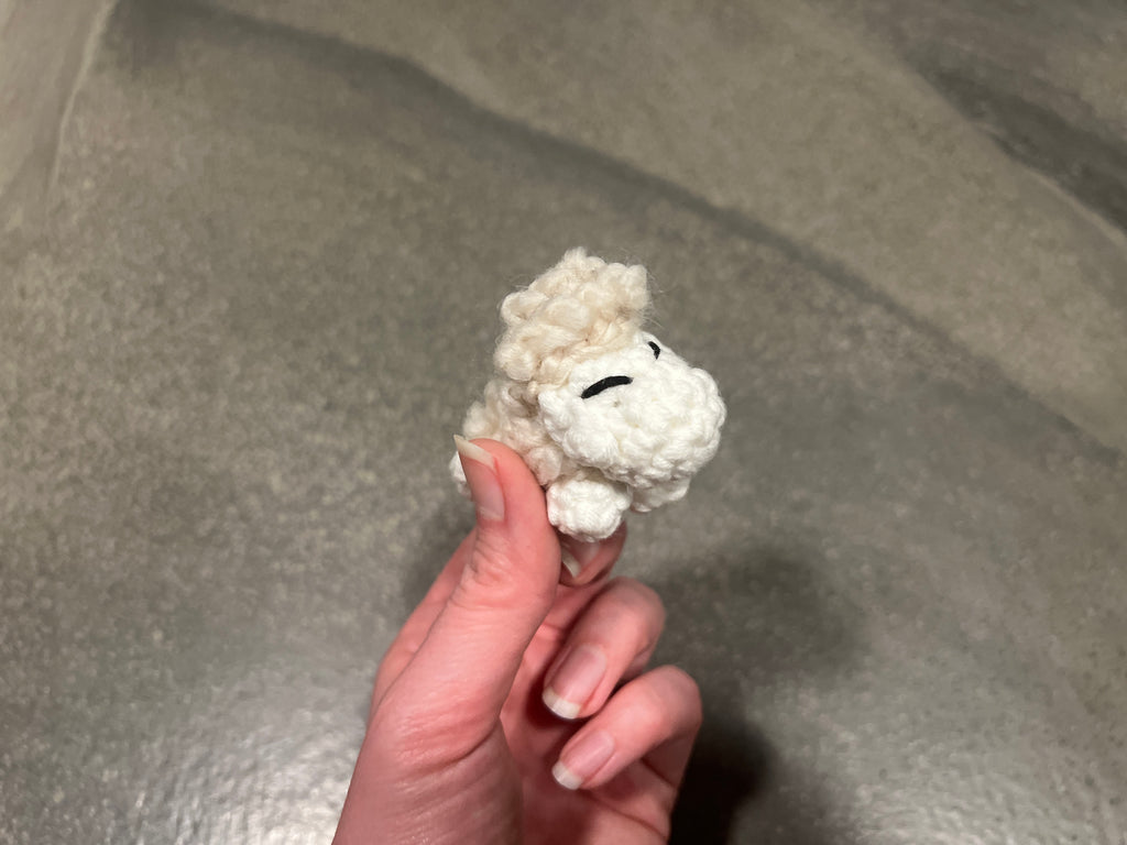 Close-up of tiny Icelandic sheep crochet figurine showing fluffy white cotton texture
